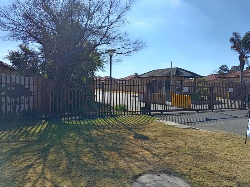 View of the secure gated entrance and guard house for the Greenhills Garden complex, featuring perimeter fencing and paved access.