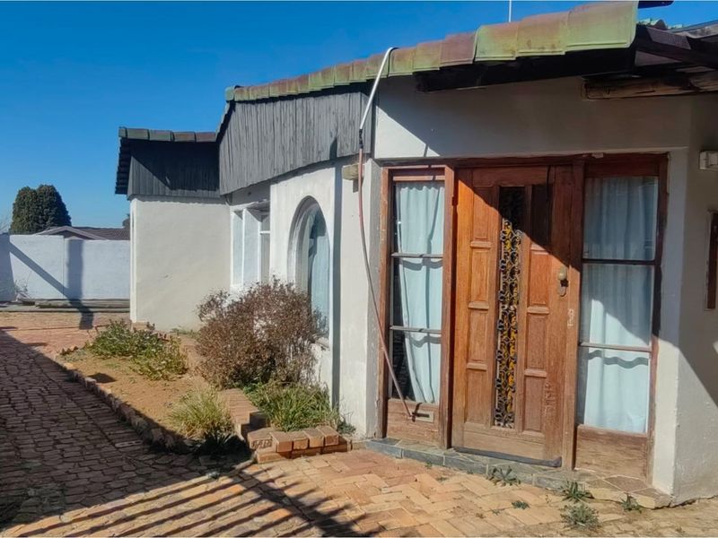 Exterior view of the property featuring a brick pathway, arched window, and a wooden entrance door with decorative metal inlay.