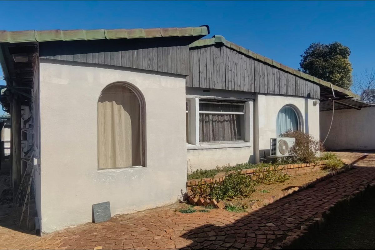 Exterior view of the property featuring a brick paved walkway, arched windows, and timber cladding under a tiled roof.