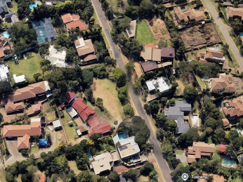 An aerial view of a residential neighborhood featuring established homes, mature trees, swimming pools, and paved street access.