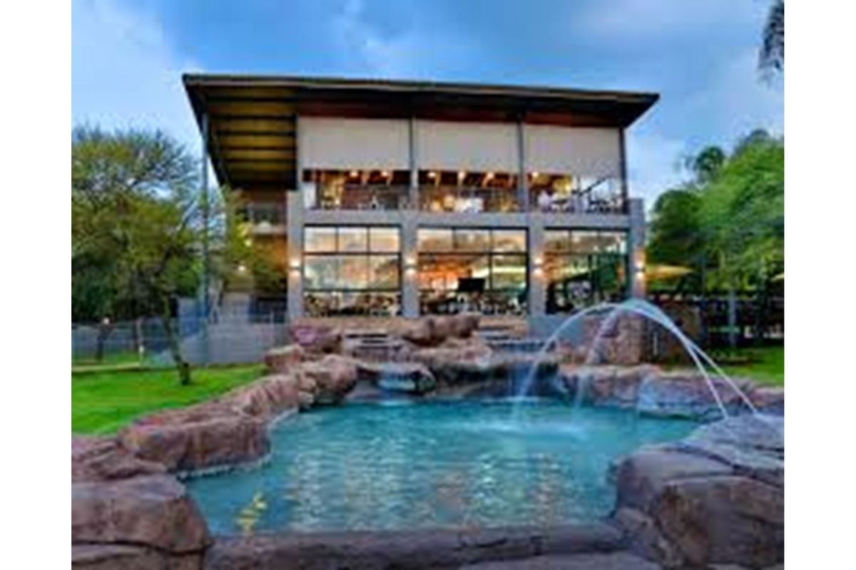 A stunning multi-level property featuring a rock-scaped swimming pool with water features, expansive glass facades, and a modern architectural design.