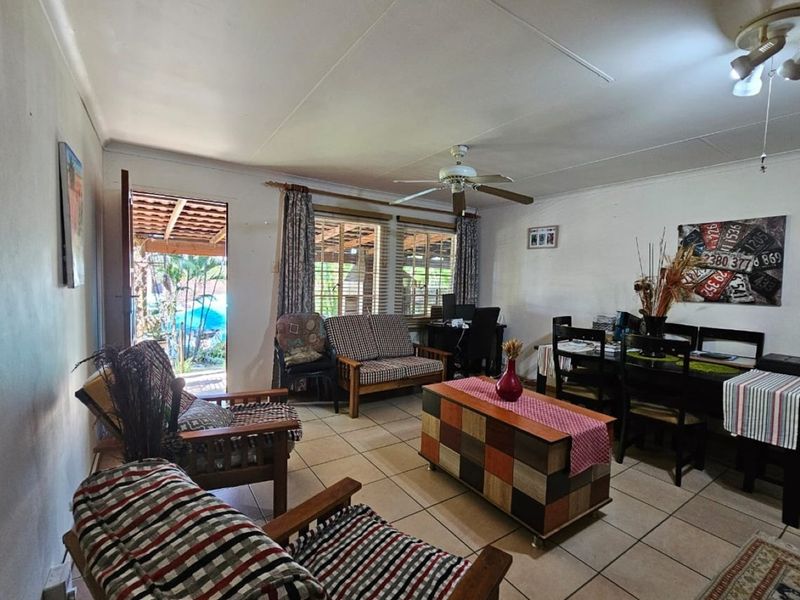 Open plan living and dining area featuring tiled flooring, a ceiling fan, and direct access to an outdoor patio space.