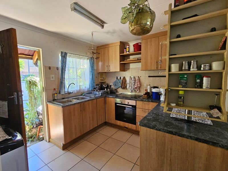 Functional kitchen featuring wood-look cabinetry, integrated oven and hob, double sink, and direct access to the exterior.
