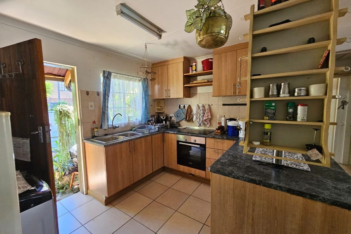 Functional kitchen featuring wood-look cabinetry, integrated oven and hob, double sink, and direct access to the exterior.