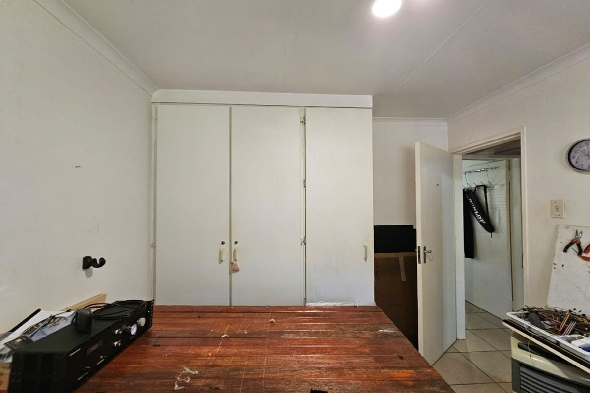 A bedroom featuring built-in cupboards and tiled flooring, offering a functional space ready for updates or personalization.