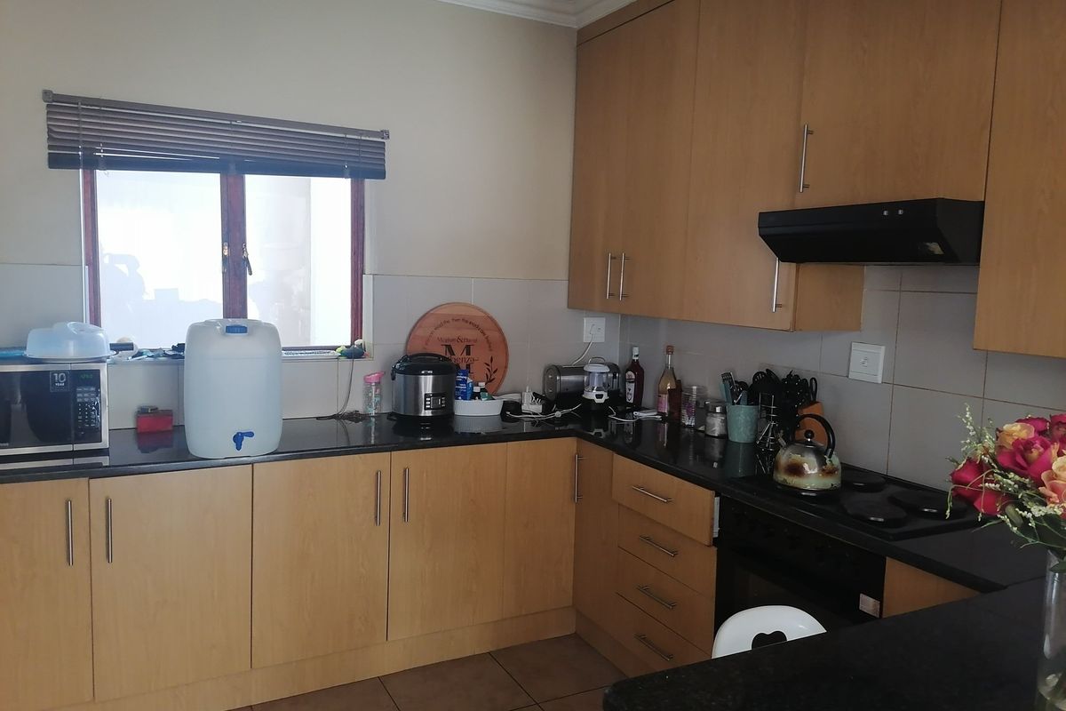 Functional kitchen featuring light wood cabinetry, dark granite countertops, built-in oven, electric hob, and extractor fan with tiled splashback.