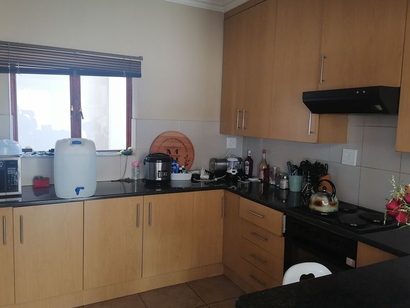 Functional kitchen featuring light wood cabinetry, dark granite countertops, built-in oven, electric hob, and extractor fan with tiled splashback.