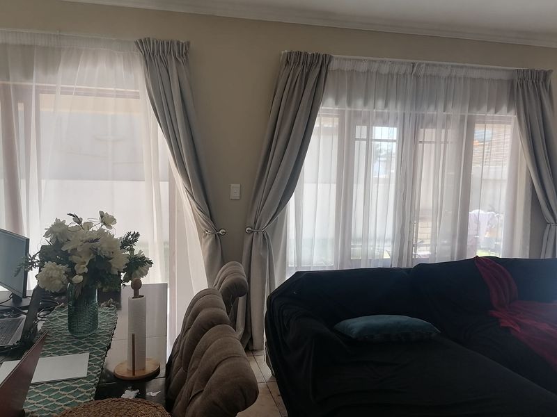 A living room area featuring tiled flooring and large glass sliding doors that provide natural light and access to the exterior.