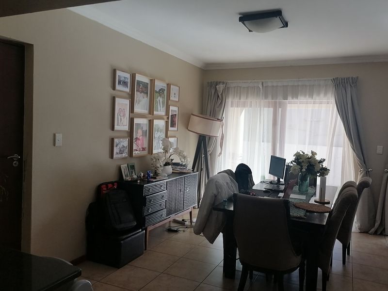 A dining room featuring tiled flooring, a coved ceiling, and a sliding glass door providing natural light.