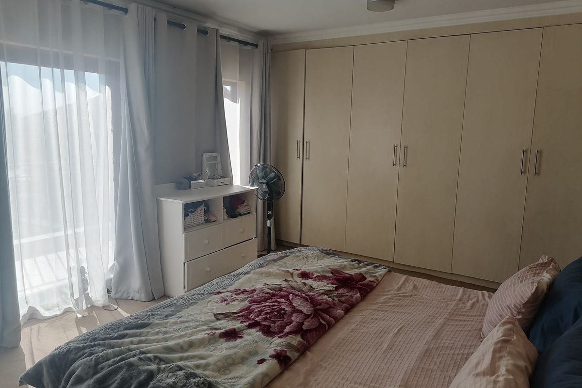 A well-lit bedroom featuring extensive built-in cupboards and a sliding glass door providing access to an outdoor area.