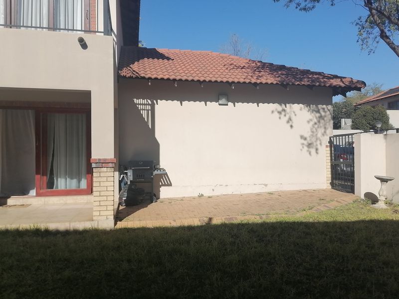 Rear view of the property featuring a paved patio area, sliding door access, and a secure gated side entrance.