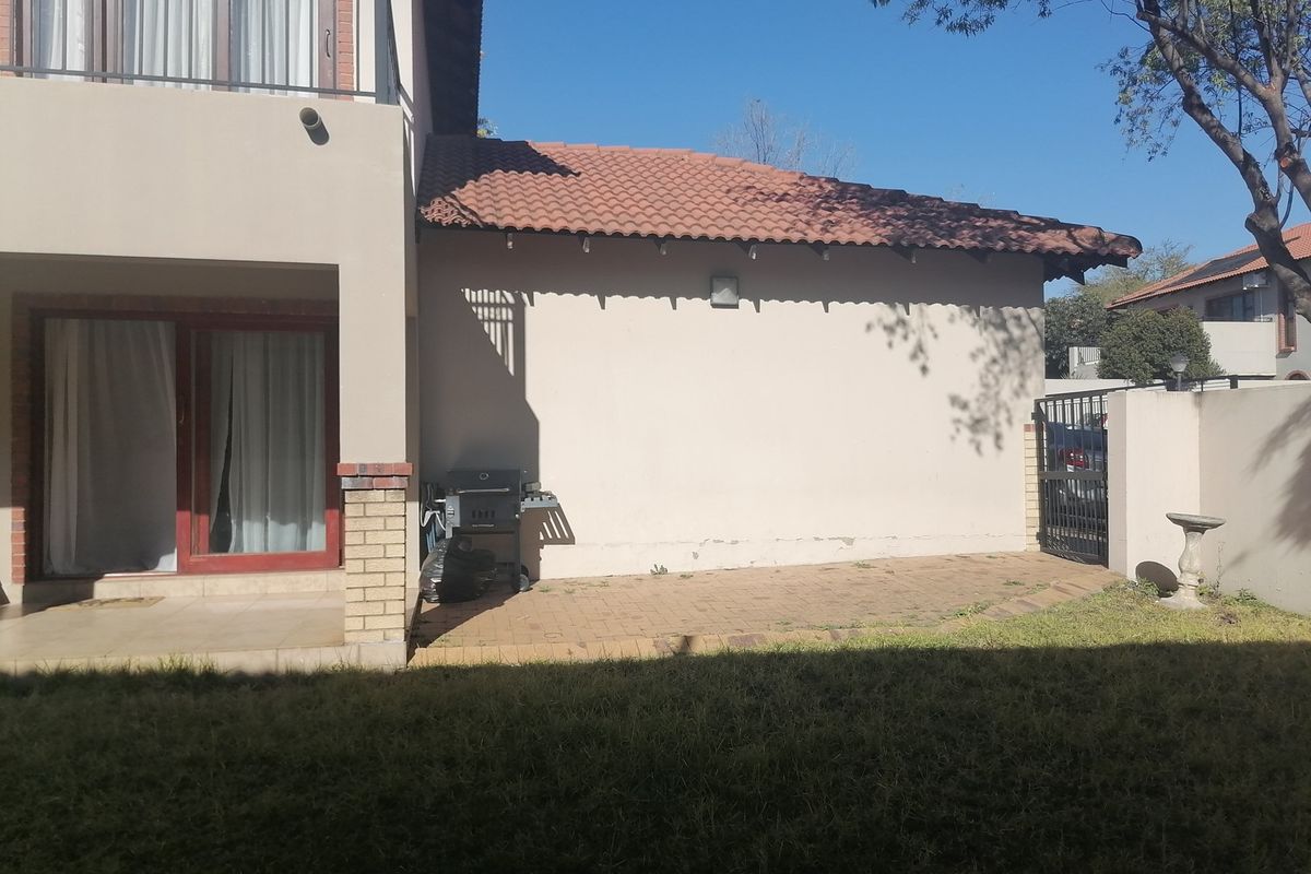 Rear view of the property featuring a paved patio area, sliding door access, and a secure gated side entrance.