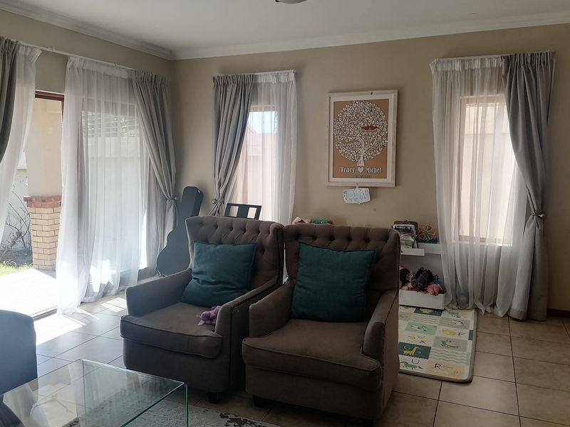 A bright living room featuring tiled flooring, coved ceilings, and large sliding glass doors that provide access to the outdoor patio area.