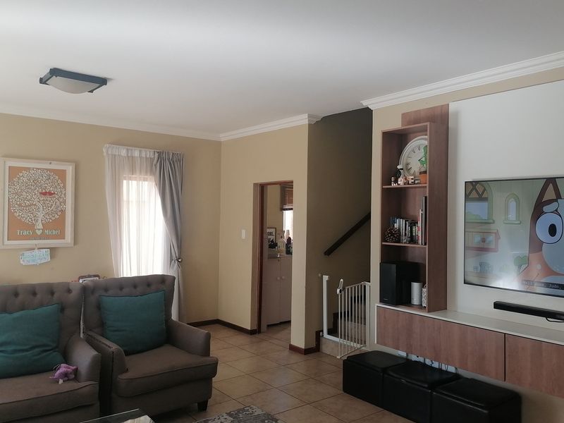 A comfortable living room featuring tiled flooring, built-in cabinetry, and access to the staircase area.