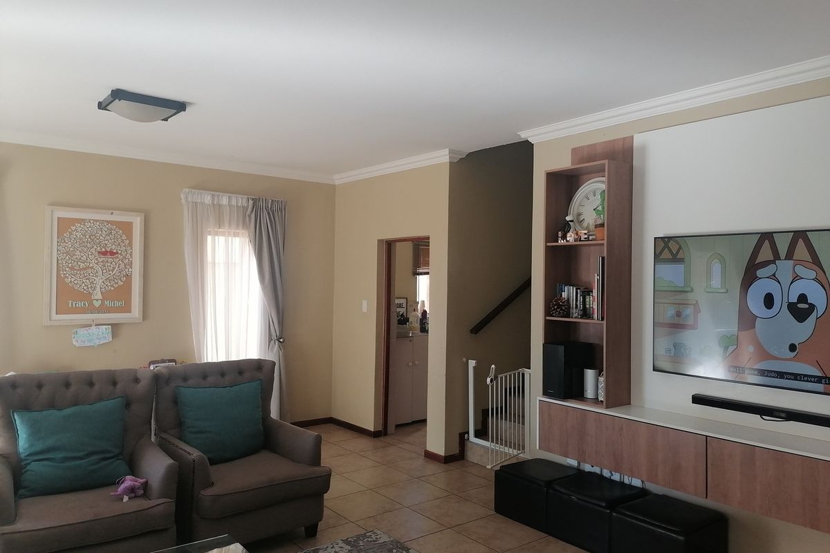 A comfortable living room featuring tiled flooring, built-in cabinetry, and access to the staircase area.