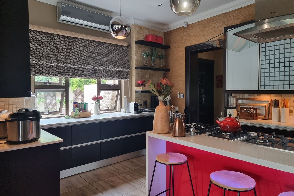 Modern kitchen featuring dark cabinetry, stone countertops, a central island with a gas hob, and integrated air conditioning unit.