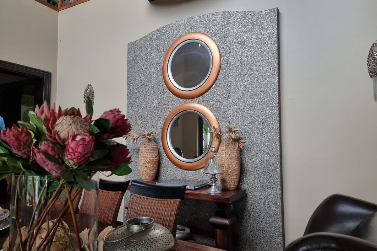 A living area featuring a decorative textured feature wall with integrated circular mirrors, adding a unique architectural element to the space.