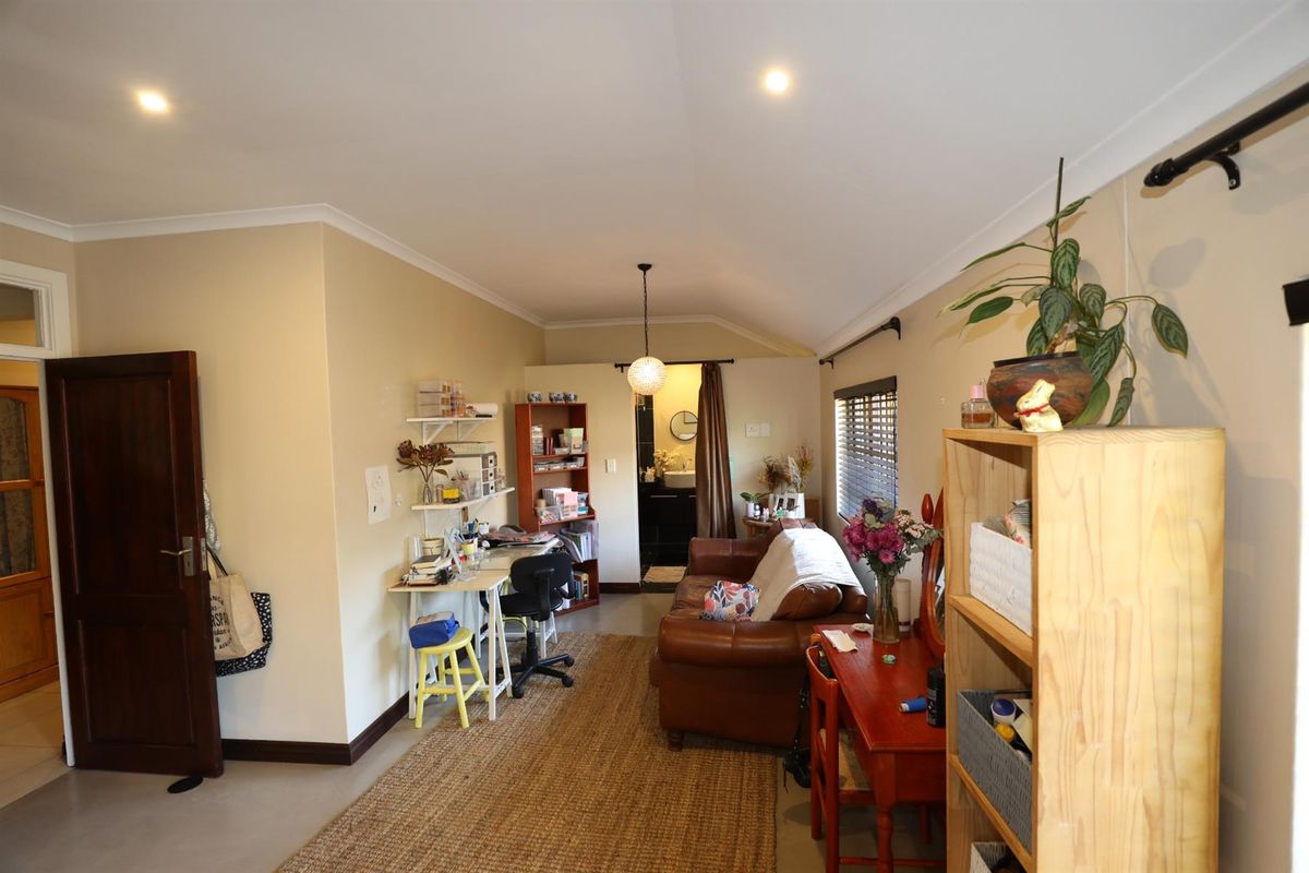 A multi-purpose living area featuring recessed downlighting, neutral wall finishes, and direct access to an adjoining bathroom space.