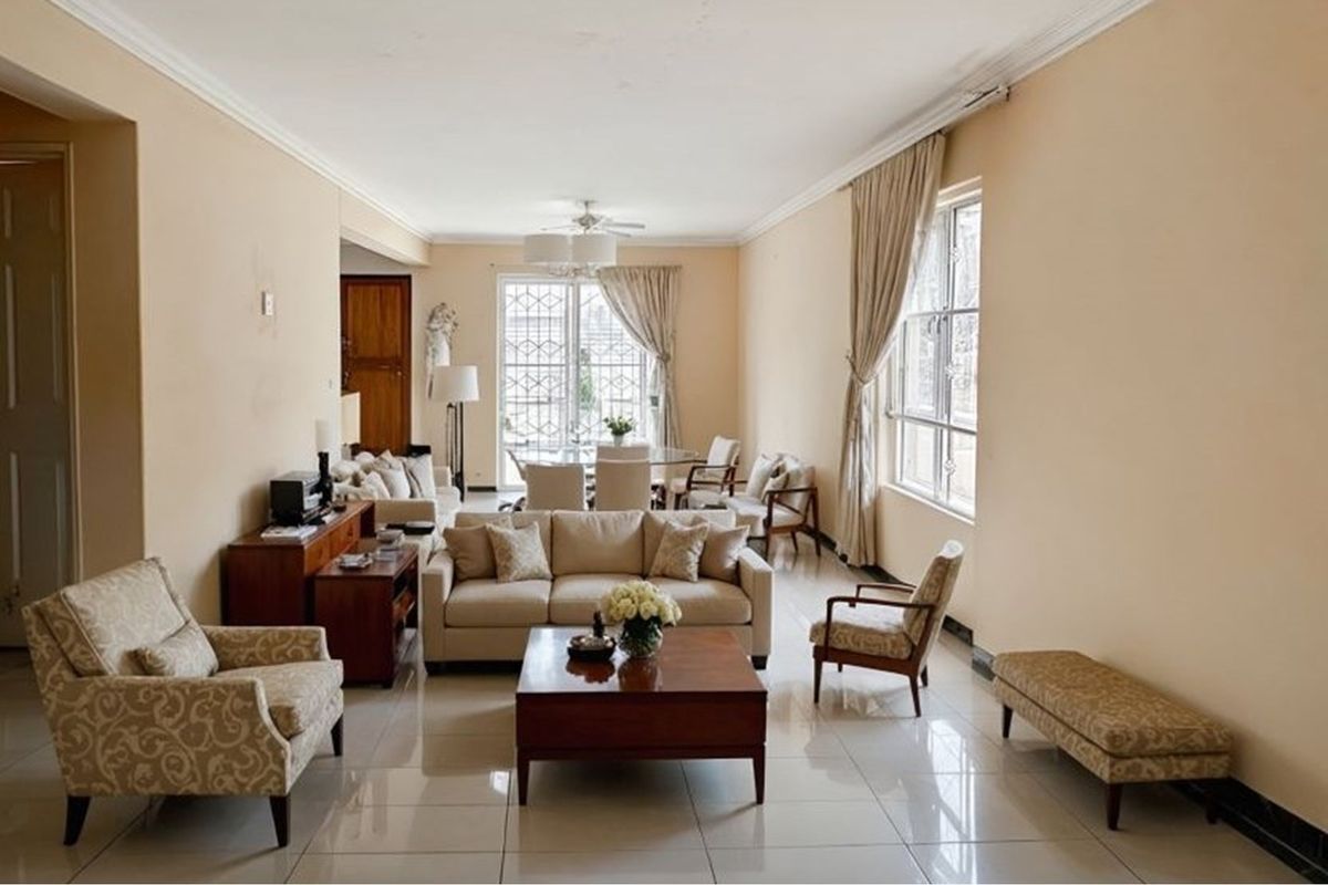 Spacious open-plan living and dining area featuring polished tile flooring, crown molding, and large windows providing natural light.