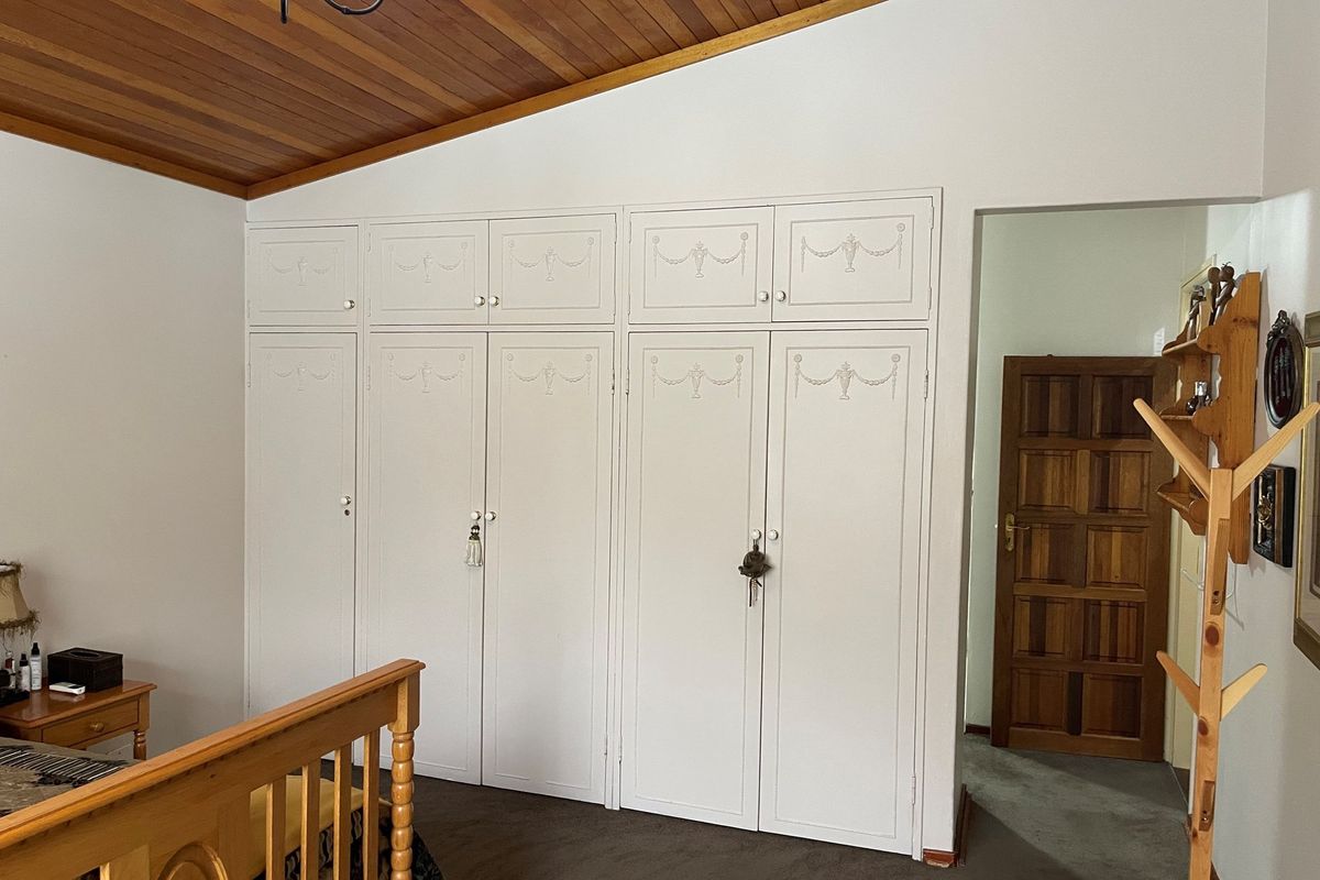 Bedroom featuring built-in floor-to-ceiling cabinetry with decorative molding and a vaulted timber-paneled ceiling.