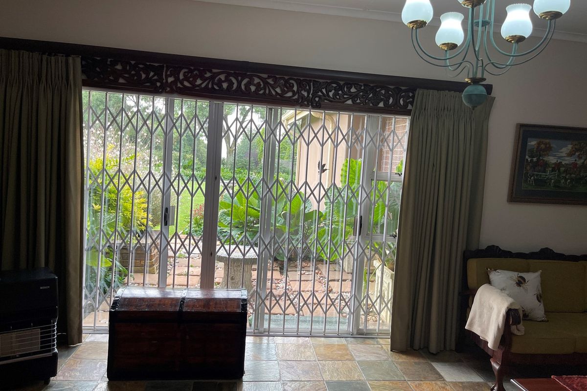 Living room featuring large sliding glass doors with security gates, providing direct access to a paved patio and garden area.