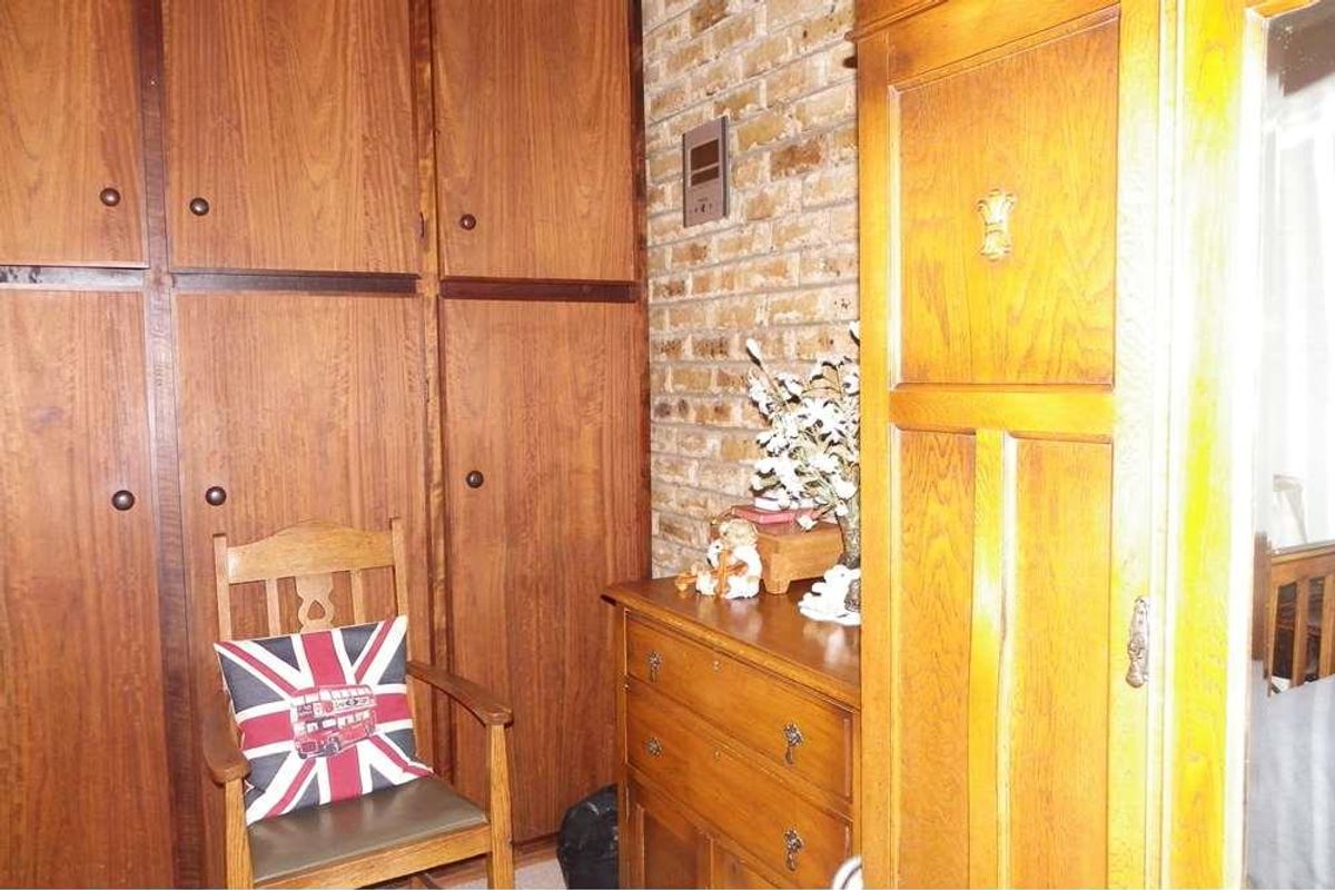 A bedroom featuring extensive built-in wooden cabinetry and a textured brick feature wall, providing ample storage and a classic aesthetic.