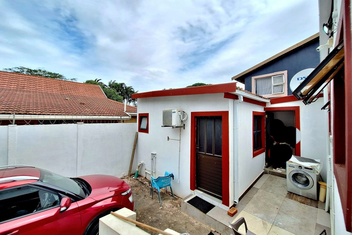 Rear exterior view of the property featuring a small tiled patio area, external air conditioning unit, and access to the main building structure.