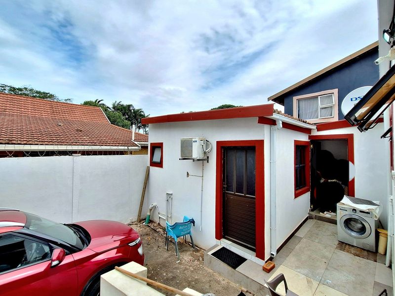 Rear exterior view of the property featuring a small tiled patio area, external air conditioning unit, and access to the main building structure.