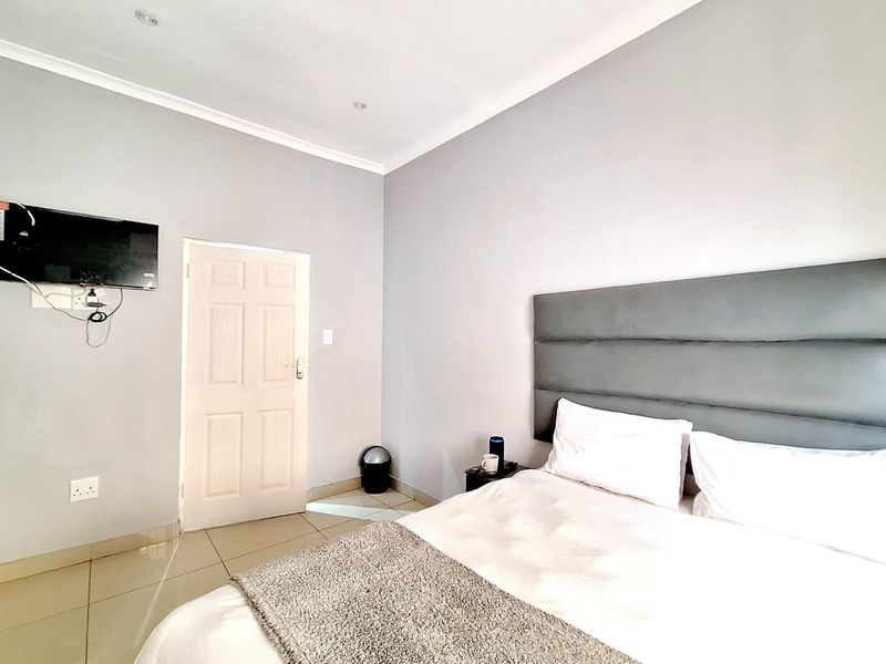 A well-maintained bedroom featuring neutral wall tones, tiled flooring, and recessed ceiling lighting.
