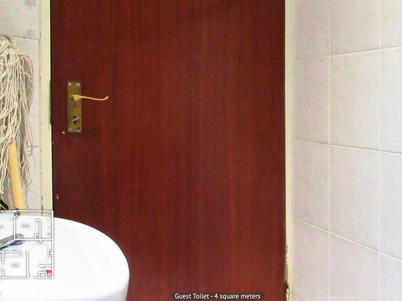 A small guest toilet featuring a pedestal basin and tiled walls, currently showing signs of wear and dated finishes.