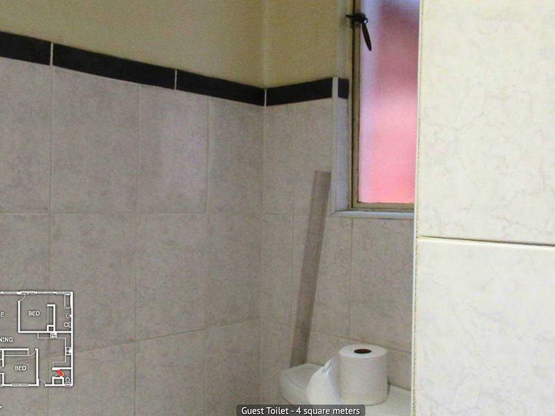 A compact guest bathroom featuring tiled walls and an obscured glass window for privacy.