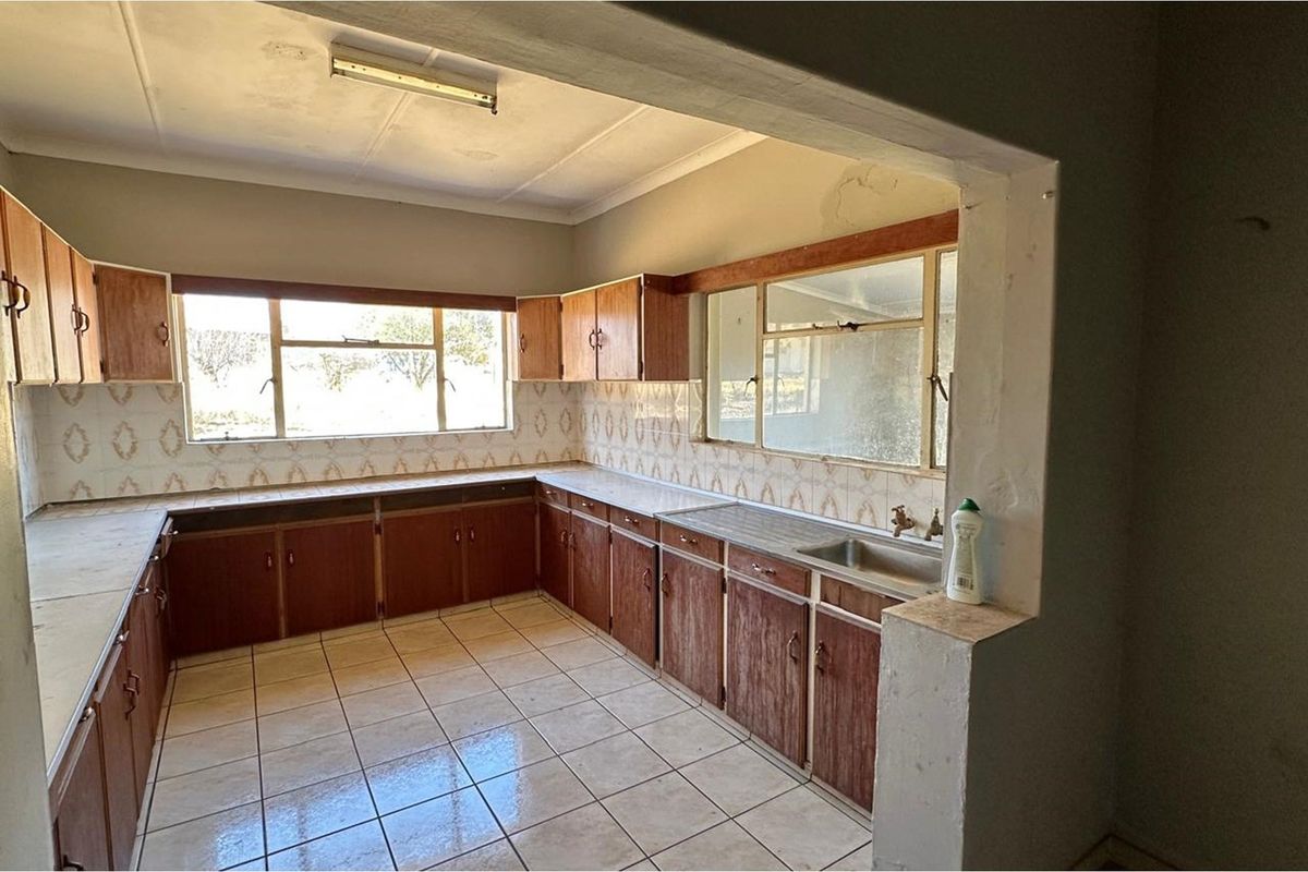 A dated kitchen featuring original laminate cabinetry, tiled splashbacks, and tiled flooring, offering a blank canvas for a modern renovation.