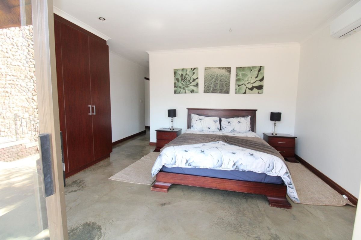 Spacious bedroom featuring built-in wooden cabinetry, polished concrete flooring, and direct access to an outdoor area through sliding glass doors.