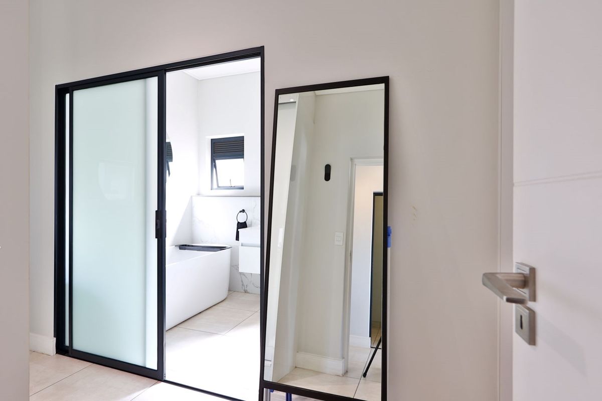 A modern bathroom featuring a sleek sliding glass door entry, tiled flooring, and a contemporary built-in bathtub with clean finishes.