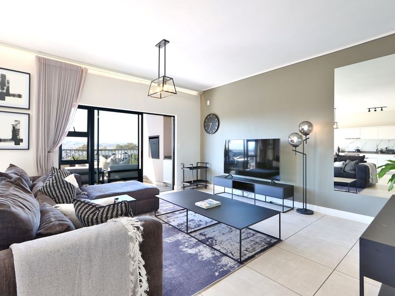 Modern open-plan living area featuring large sliding doors leading to a balcony, neutral tiled floors, and contemporary lighting fixtures.
