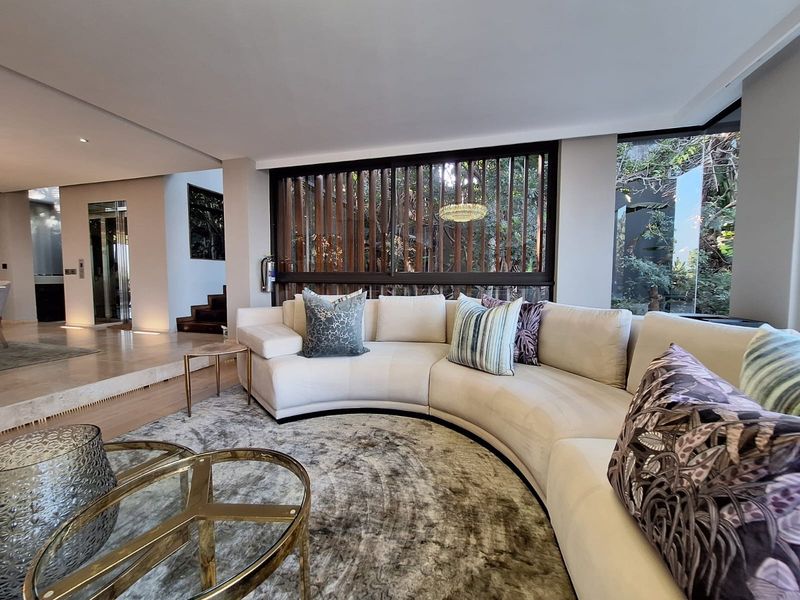 A sophisticated living room featuring high-end stone flooring, a unique timber slat window screen, and a modern glass elevator, creating a luxurious open-plan atmosphere.