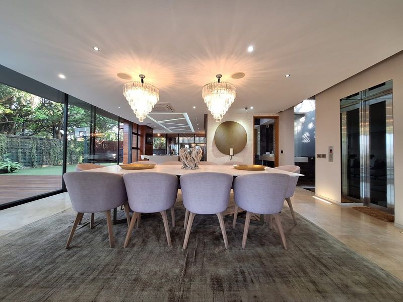 Elegant dining area featuring floor-to-ceiling glass walls, modern recessed lighting, and a private integrated elevator, offering a seamless transition to the outdoor space.