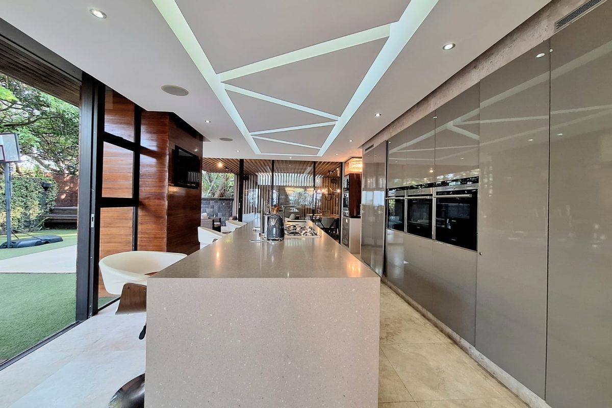 Modern kitchen featuring a large stone island, integrated high-end appliances, sleek cabinetry, and expansive sliding glass doors opening to the outdoor area.