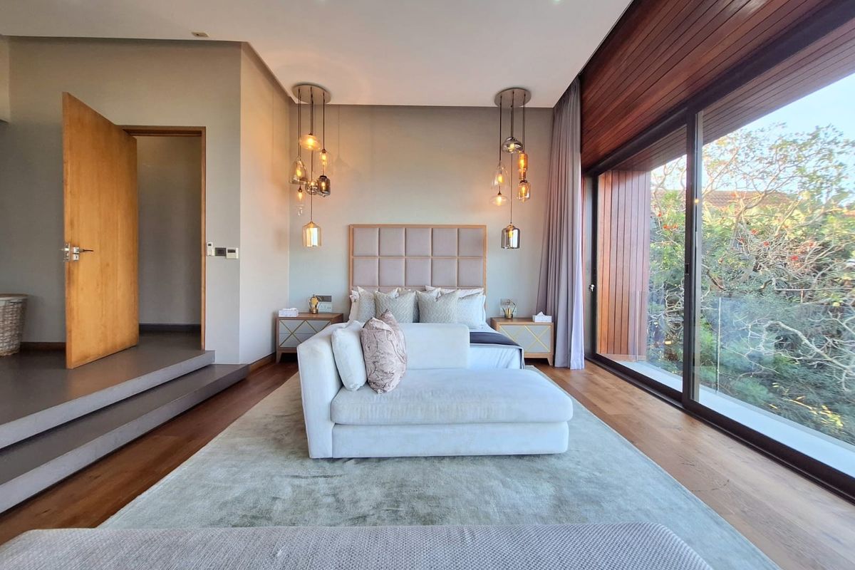 A modern, well-appointed bedroom featuring hardwood floors, floor-to-ceiling glass doors with timber accents, and elegant recessed lighting.