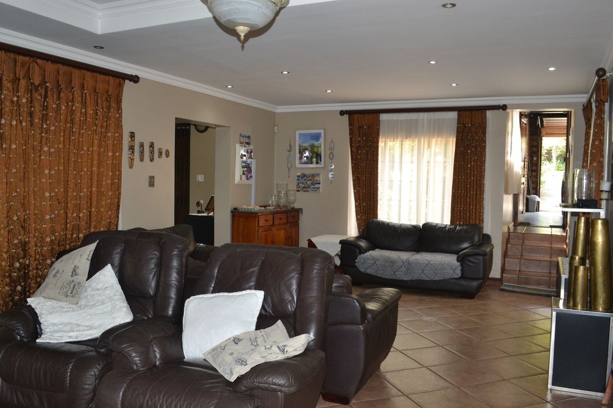 Spacious living area featuring tiled flooring, recessed ceiling lighting, and large windows with curtain treatments, providing access to adjacent rooms.