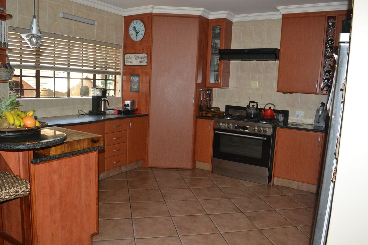 A functional kitchen featuring wood-finish cabinetry, tiled splashbacks, a built-in oven with extractor fan, and tiled flooring.