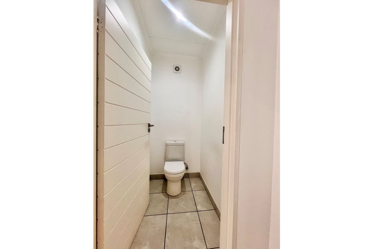 A compact, functional guest toilet featuring tiled flooring, a standard toilet suite, and an integrated extractor fan.