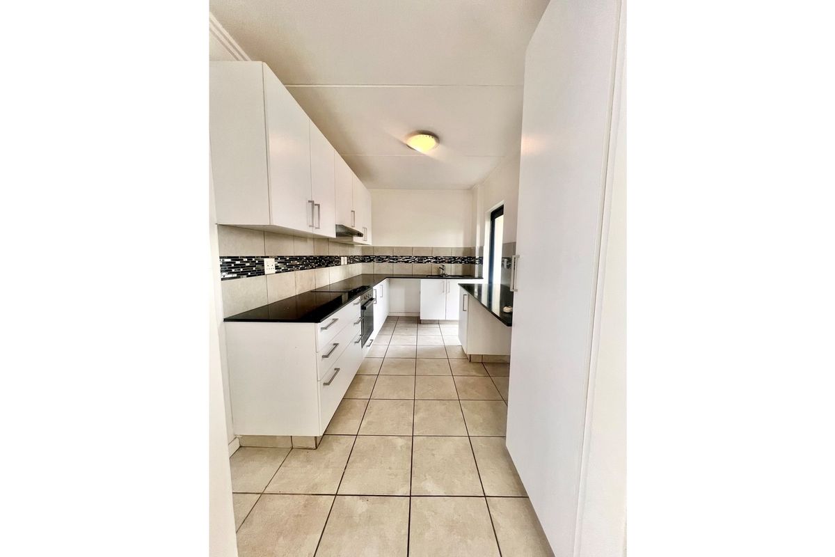 A functional kitchen featuring white cabinetry, dark countertops, a built-in oven, and tiled flooring in a clean, neutral layout.