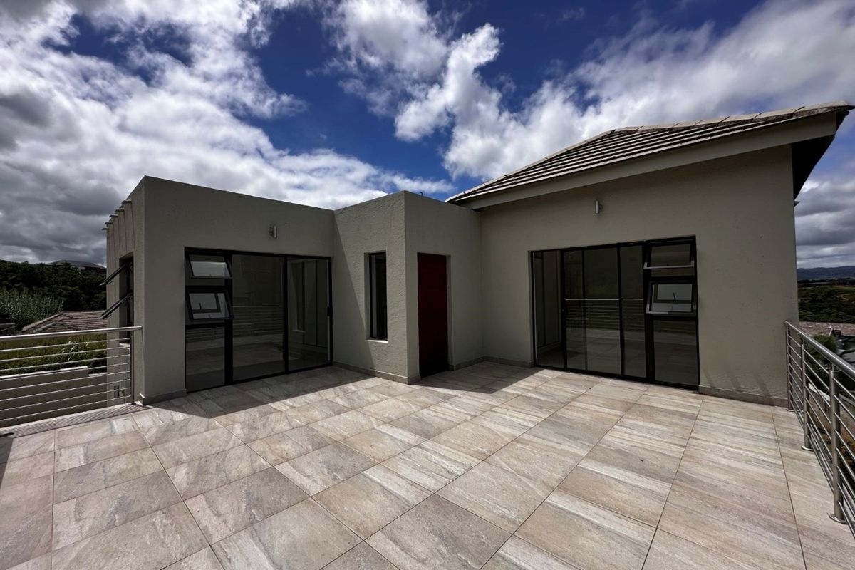Spacious outdoor terrace featuring modern tiled flooring, aluminum-framed sliding doors, and stainless steel balustrades, offering a clean and well-maintained exterior living space.