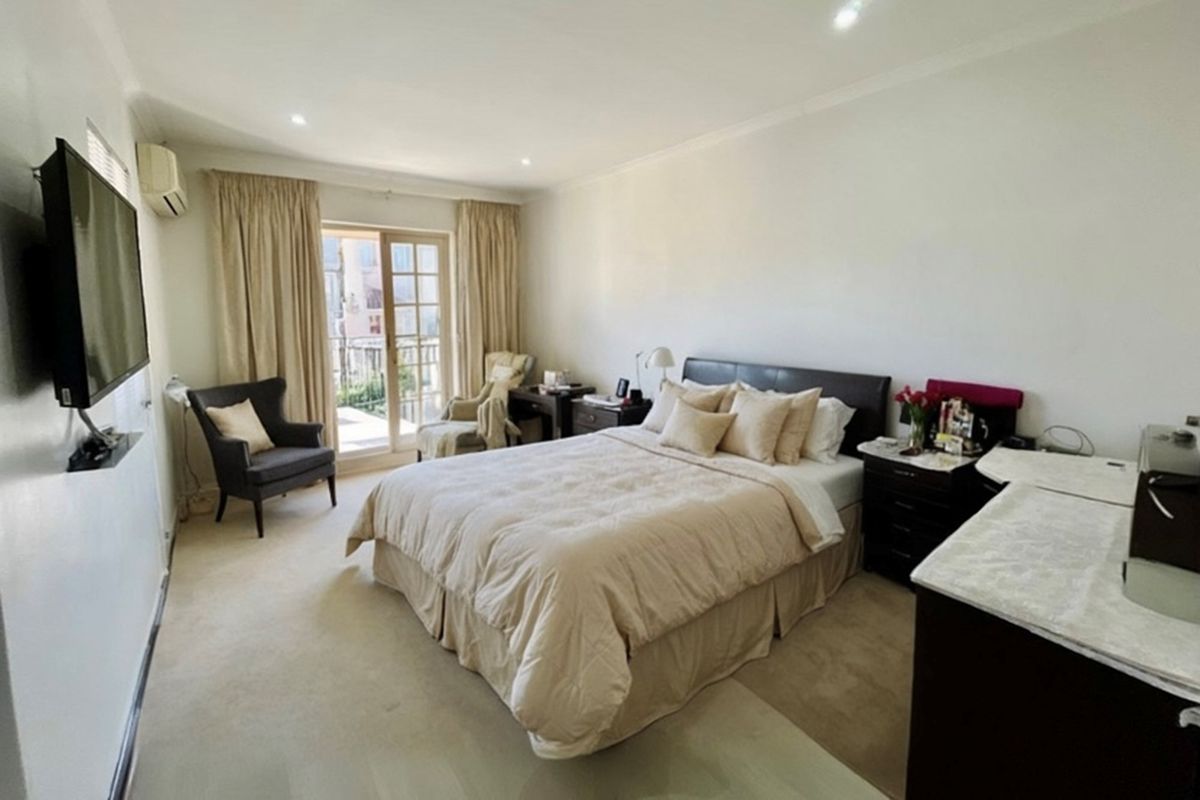A spacious bedroom featuring neutral carpeting, recessed lighting, and a glass sliding door providing access to a private balcony.