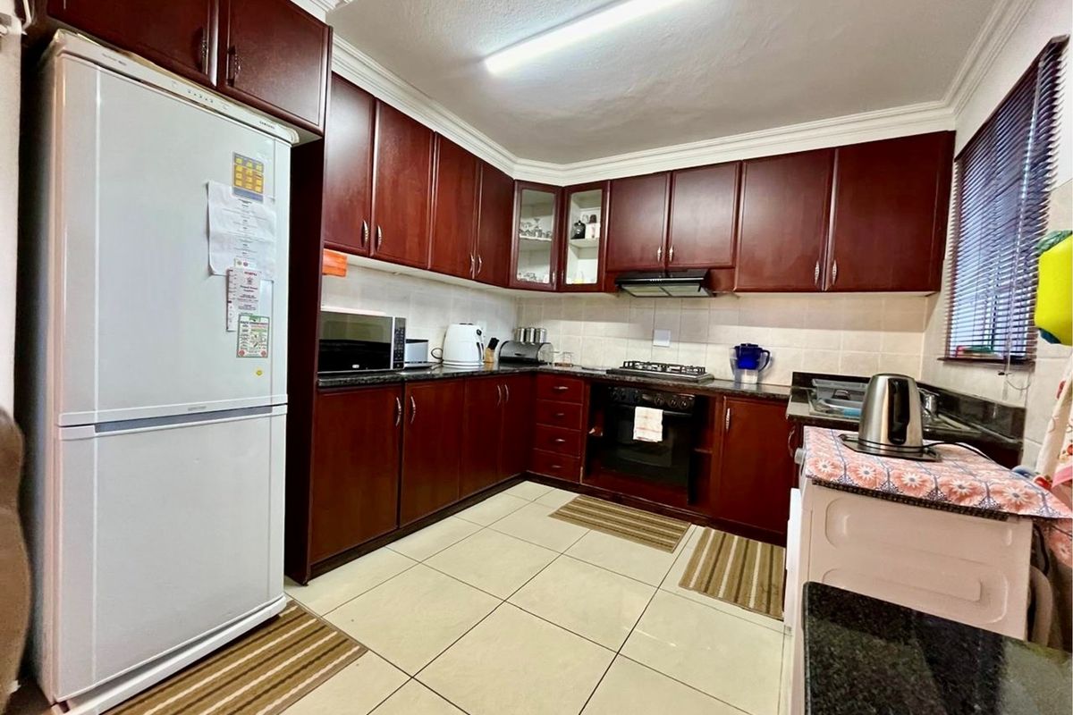 A functional kitchen featuring dark wood cabinetry, granite countertops, a built-in oven with gas hob, and tiled flooring.