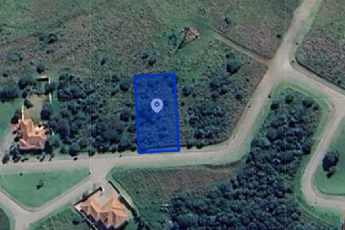 Aerial view of a vacant residential plot highlighted in blue, situated within a developed neighborhood with established road access and surrounding vegetation.