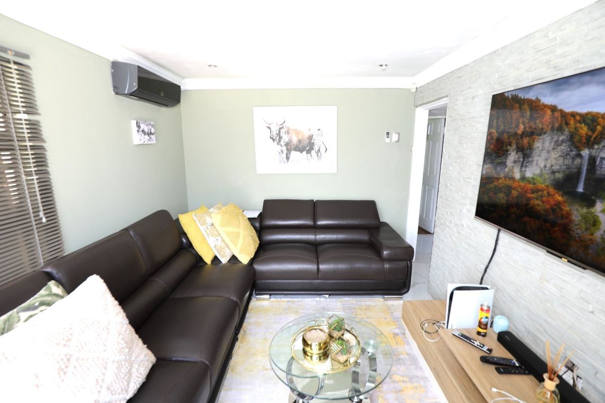 A comfortable living room featuring a textured stone feature wall, split-system air conditioning unit, and tiled flooring.