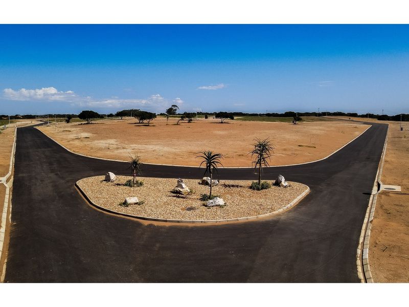 Aerial view of a residential development site featuring paved roads, concrete curbing, and a landscaped traffic island.