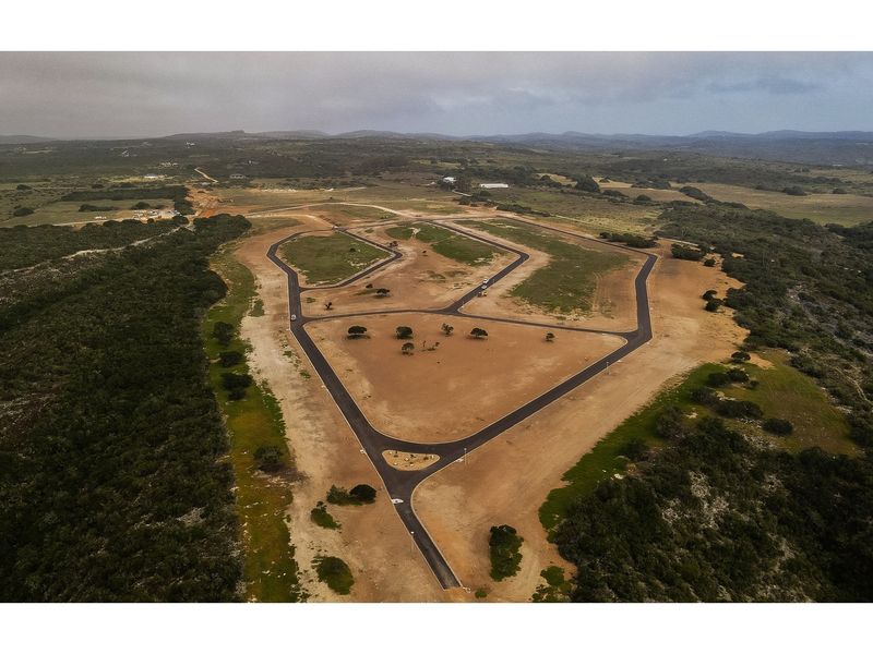 Aerial view of a residential land development featuring newly paved roads and cleared plots set within a natural landscape.